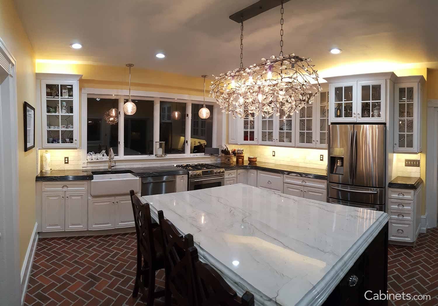 Long textured chandelier over a black island with white marble countertops