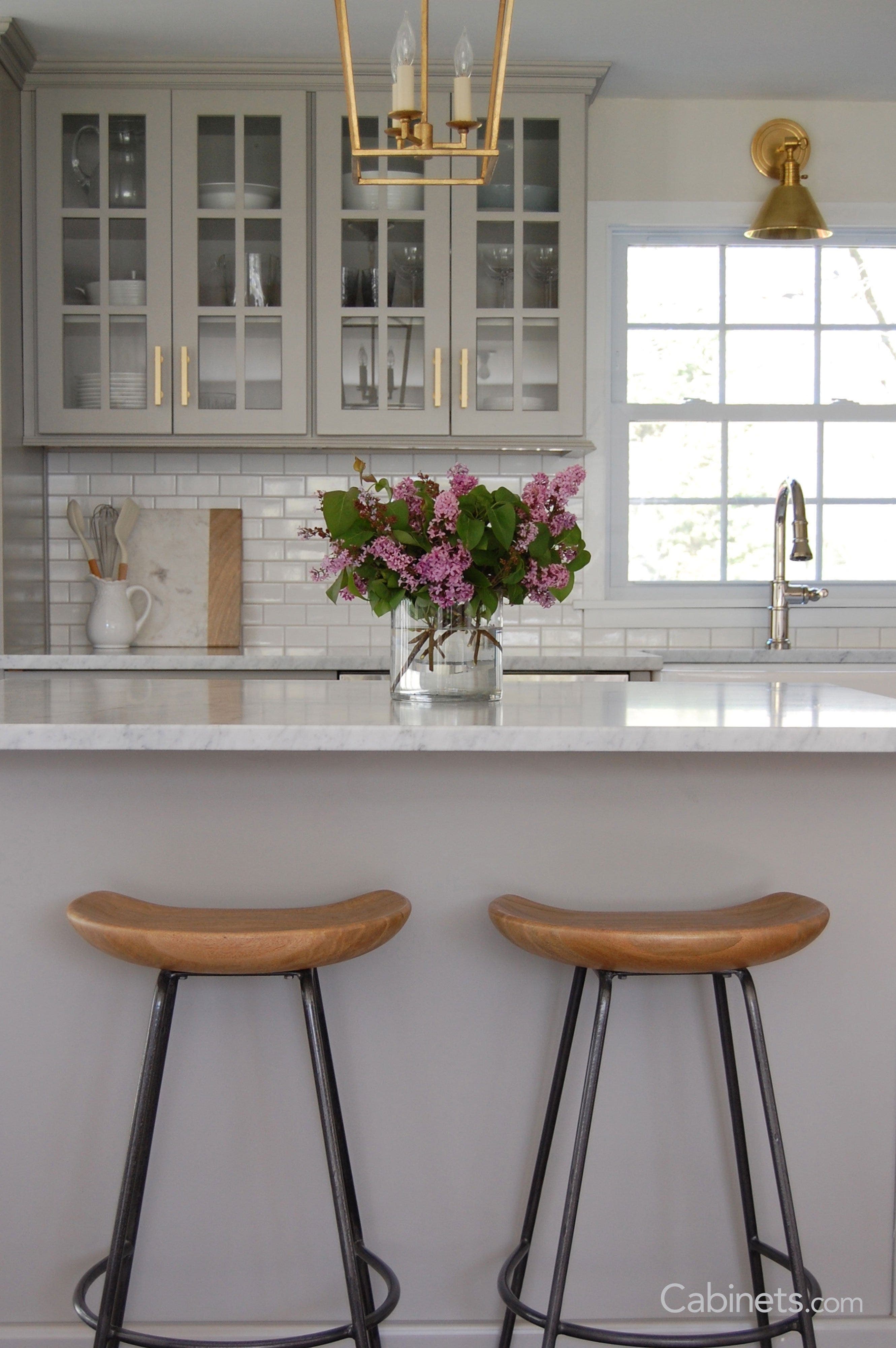 Willow grey cabinets with gold hardware and decorated with bright flowers