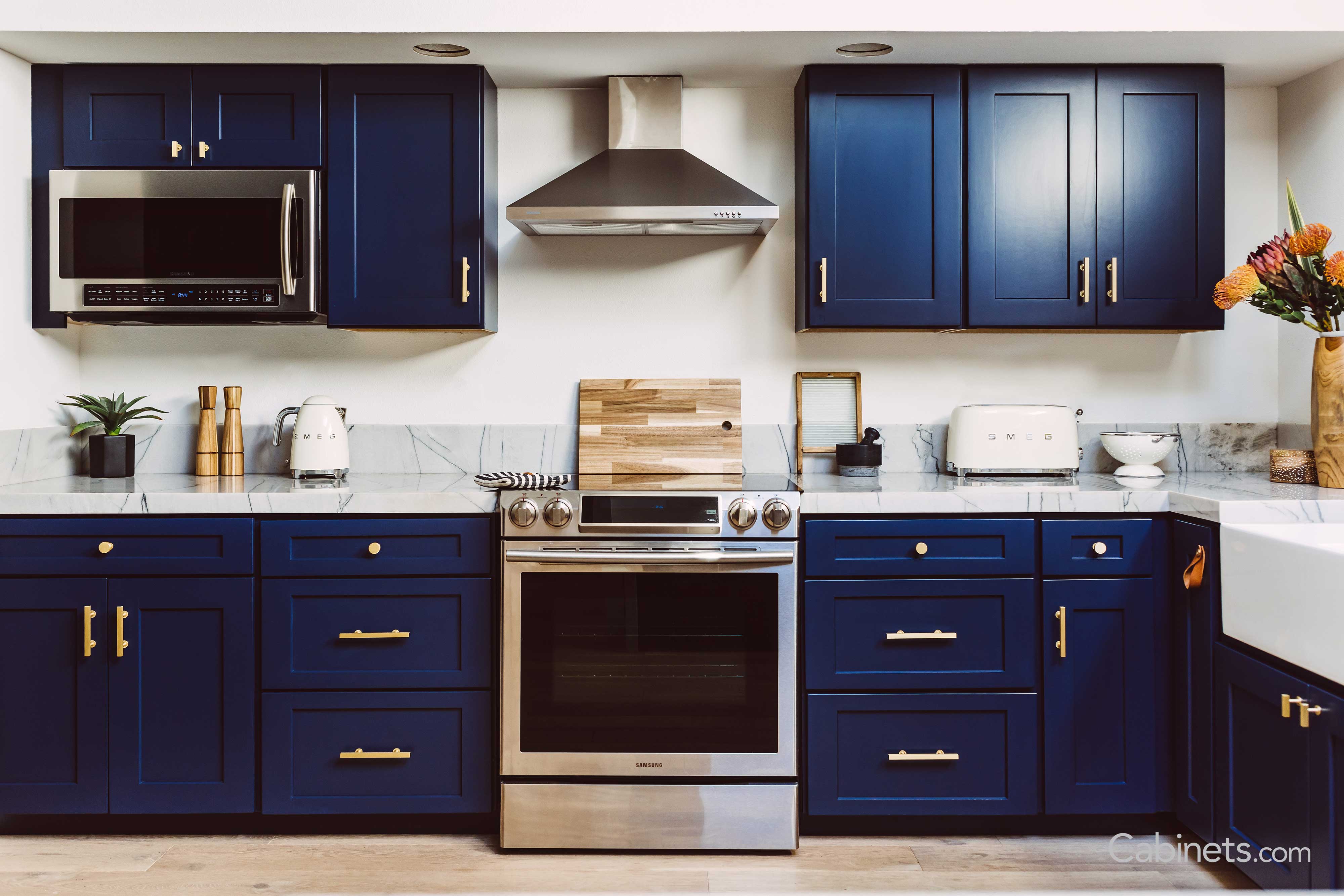 Midcentury modern style kitchen with navy blue cabinets and gold hardware.