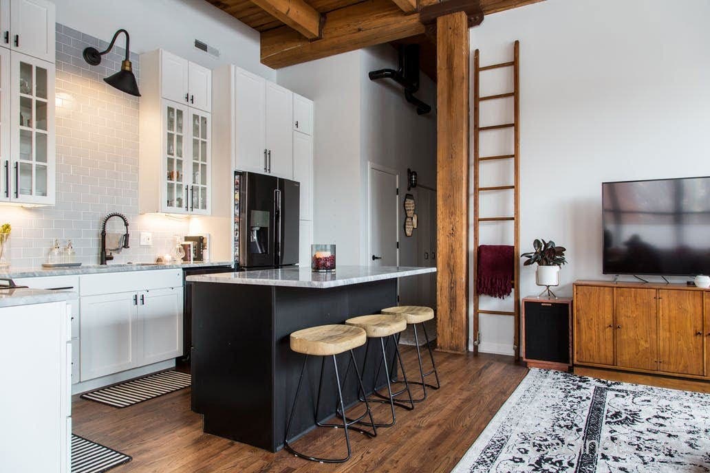 Black lamp attached to grey subway tile wall above sink 