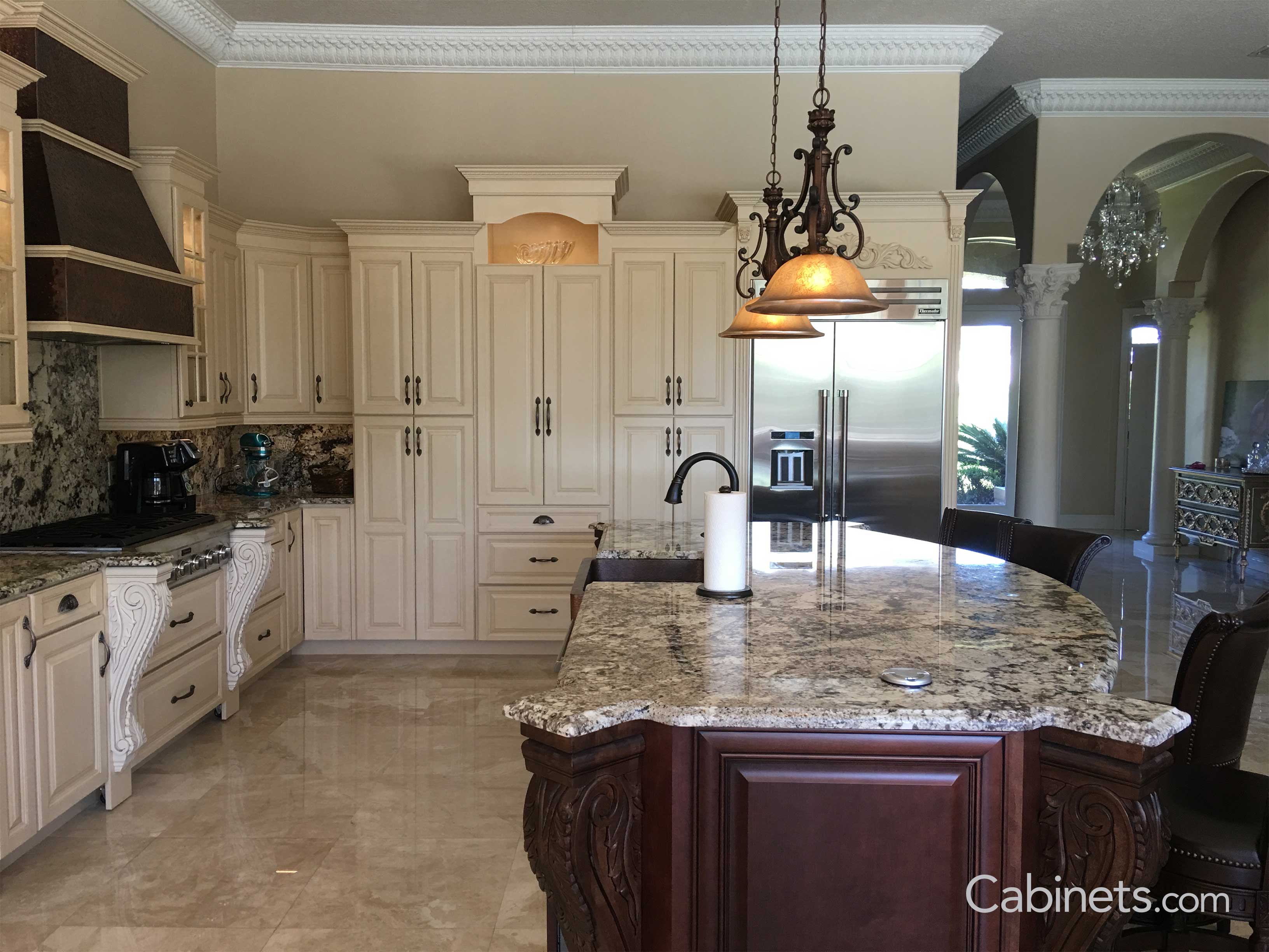 Antique white with brushed brown glaze cabinets with corbels with a botanical design