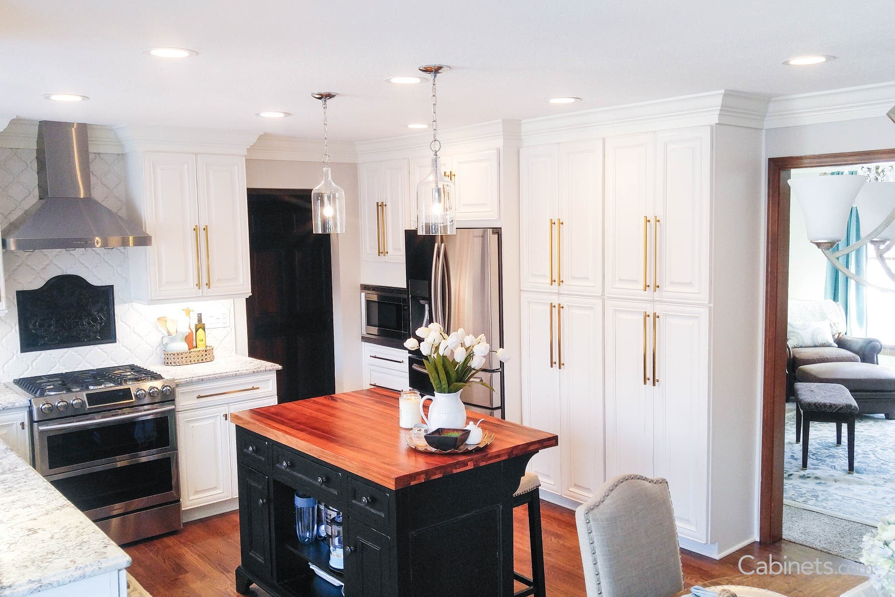 Bright white cabinets with gold bar pulls and a black island with black knobs