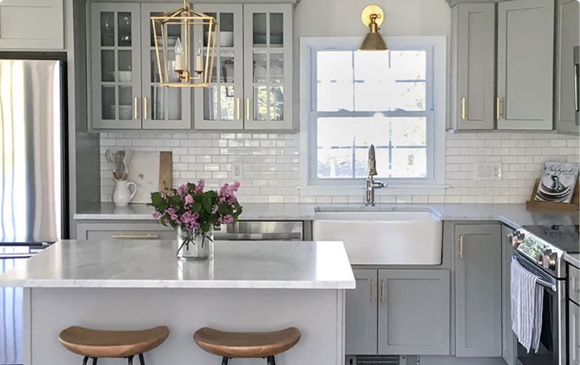 Light gray kitchen cabinets with gold hardware and
                        glass mullion doors