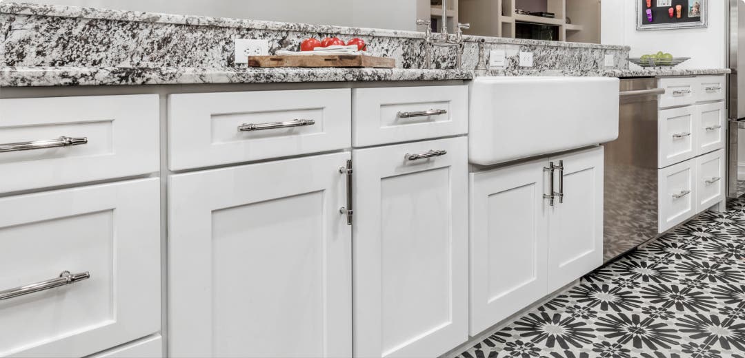 Bright White Shaker style kitchen cabinets with brushed nickel hardware and black-and-white counter tops